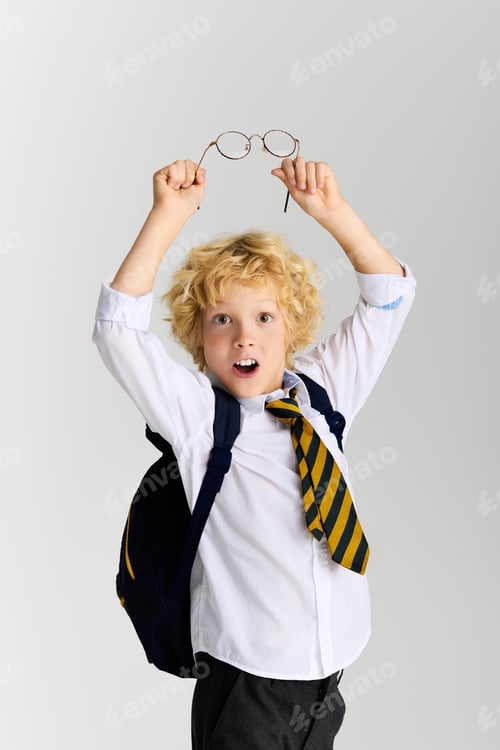 Visualização: Estudante animado com óculos comemora de uniforme contra um fundo neutro