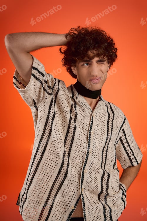 Preview: Stylish young man in a trendy shirt posing against a vibrant orange backdrop with flair