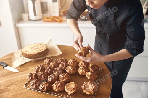 Preview: young professional female cook is preparing tasty cake at her light modern kitchen