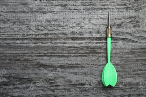 Preview: Green dart arrow on grey wooden table, top view with space for text
