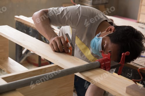 Preview: Shallow focus of a Southeast Asian carpenter working on polished wood planks in the workshop