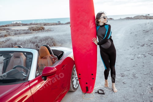 Preview: Young woman with surfboard on the rocky coast