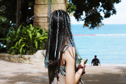 Preview: Teenager girl with blue ribbon braided hairstyle walking in the beach ocean view