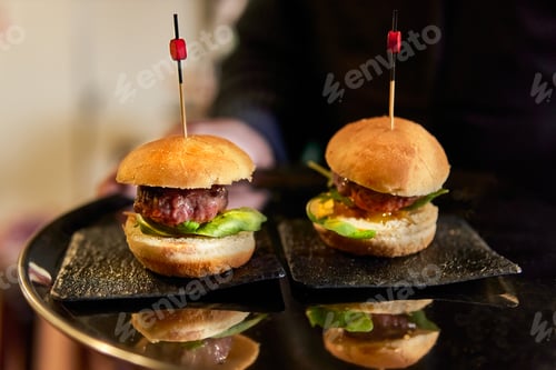 Preview: Waiter offering hamburger snack tapas on a tray at a catering workshop