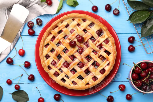 Preview: Tasty cherry pie and berries on light blue wooden table, flat lay