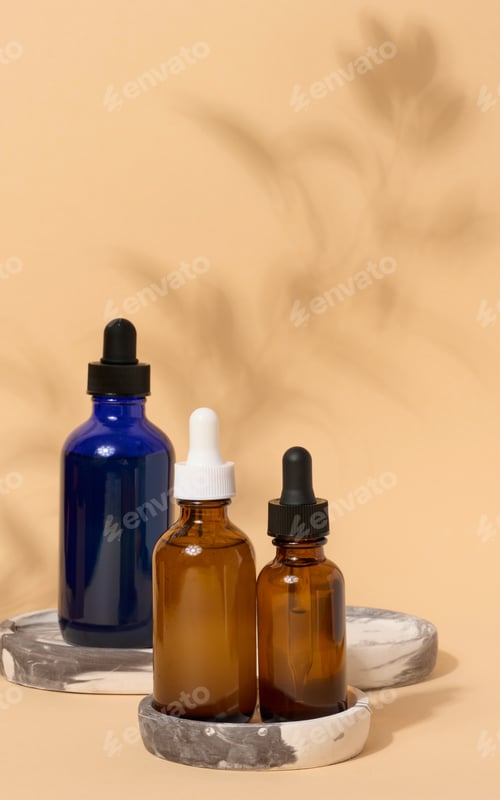 Preview: Glass bottles with pipettes on a beige background with a shadow from a branch.