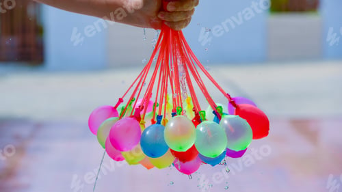 Preview: Colorful water balloons playing with small plastic pool on summer holiday.