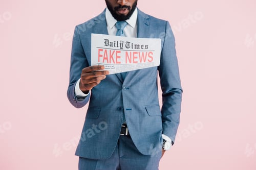 Preview: cropped view of african american businessman reading newspaper with fake news isolated on pink