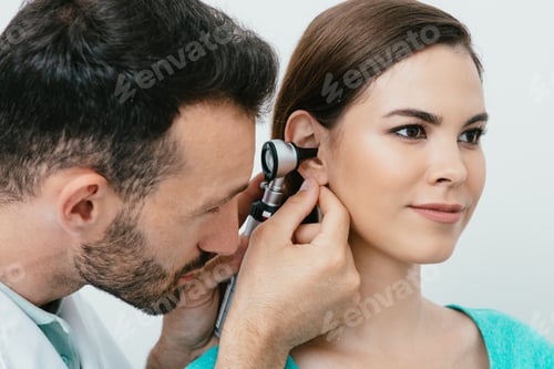 Preview: Hearing exam. Hispanic woman during a hearing test, an audiologist with an otoscope checking