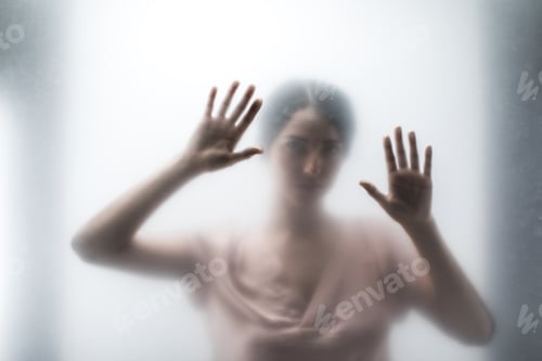 Preview: Silhouette of woman looking through the glass and touching it with hands