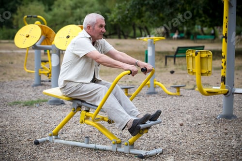 Preview: Old man making exercises on outdoor gym.
