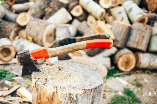 Preview: A sharp blade of an ax that sticks out in a wooden chock. rustic concept