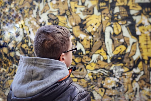 Preview: Young male teenager in a winter outfit looking a wall graffiti