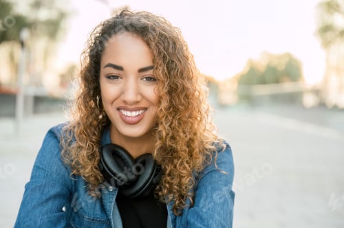 Preview: Smiling woman with wireless headphones on street