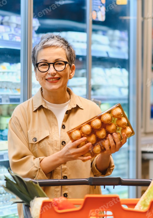 Preview: Happy senior woman buying eggs in grocery store