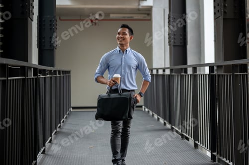 Preview: A handsome and confident Asian millennial businessman walking along the building corridor.