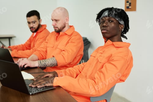 Preview: Portrait of Young Black Man Sitting with Coworkers Using Laptops in Office