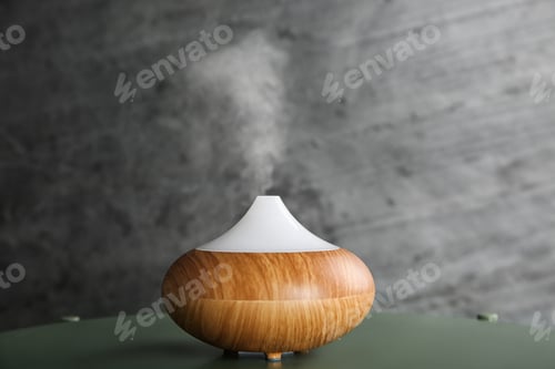 Preview: Modern essential oil diffuser on green table against dark grey background