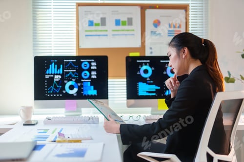 Preview: Professional businesswoman analyzing business data on multiple screens