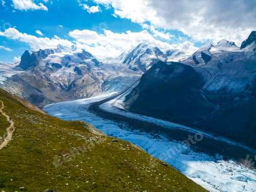 Preview: a path winds through a valley in the middle of the mountains