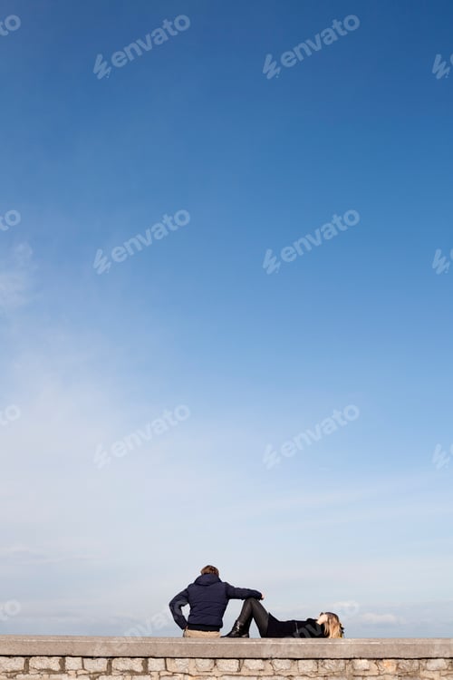 Preview: Young couple watching the horizon with blue sky