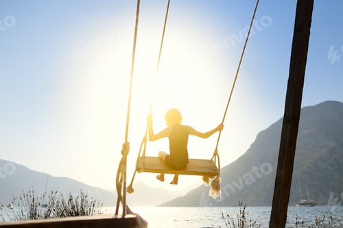 Preview: Little boy having fun on large swing on the shore in the Boka Kotor Bay of the Adriatic Sea