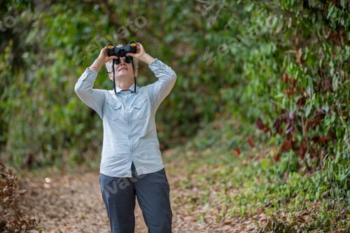 Preview: Senior woman is hiking outdoors, enjoying nature expression looks into the distance observing