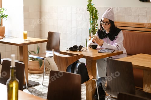 Preview: Young asian woman using gadgets while drinking coffee