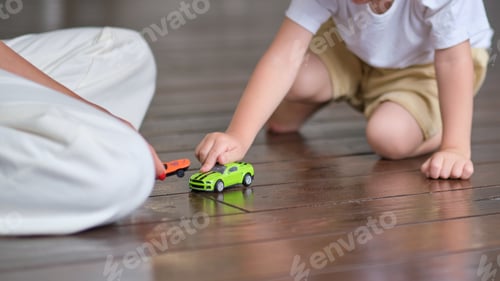 Preview: Expressive baby boy playing with a toy car with mother.
