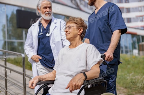 Preview: Nurse and doctor talking to patient on wheelchair in hospital yard during walk