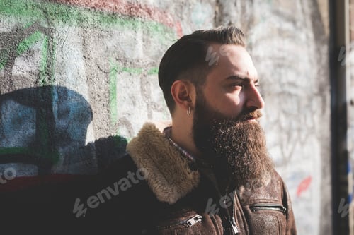 Preview: Young bearded man by graffiti wall