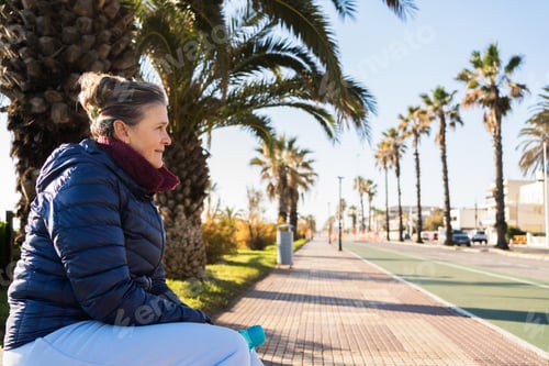 Preview: Senior woman relaxing after rollerskating on palm lined promenade