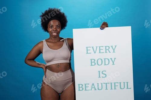 Preview: Happy active plus size woman holding poster saying thet every body is beautiful