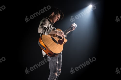 Preview: Guitarist Playing Acoustic Guitar in Dramatic Spotlight