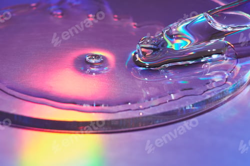 Preview: Pipette with sample of cosmetic product in petri dish on iridescent holographic background