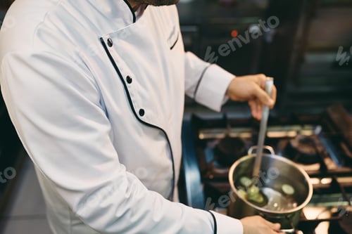 Preview: Unrecognizable chef cooking while working in the kitchen at restaurant.