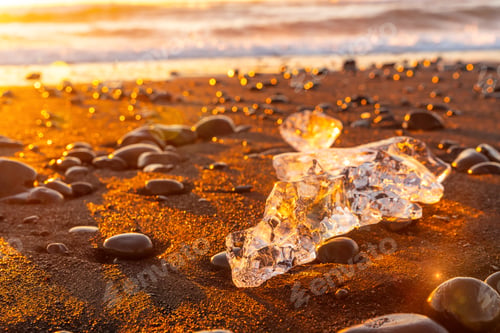 Preview: Ice and stones at sunrise with ice on Diamond Beach next to Jokulsarlon in winter in Iceland