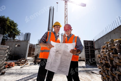 Preview: Structural engineer and construction manager in orange work vests and hard helmets discuss