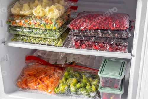 Preview: Plastic bags with different frozen vegetables and berries in refrigerator.