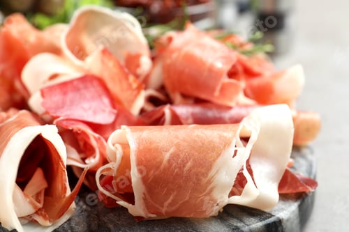 Vista previa: Pile of tasty prosciutto on table, closeup