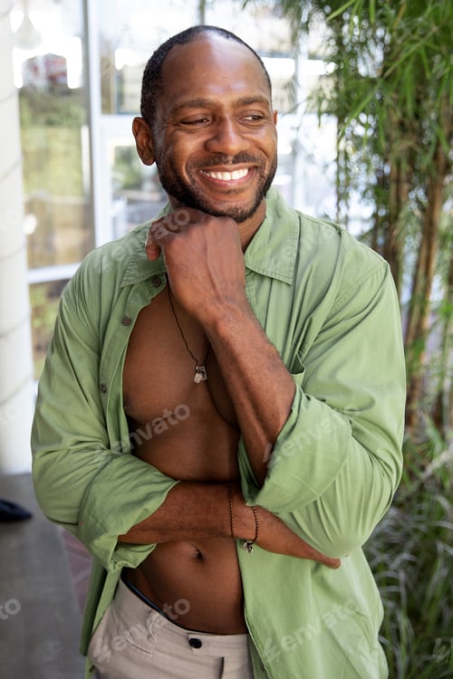 Vista previa: Handsome happy black man in green shirt enjoying day