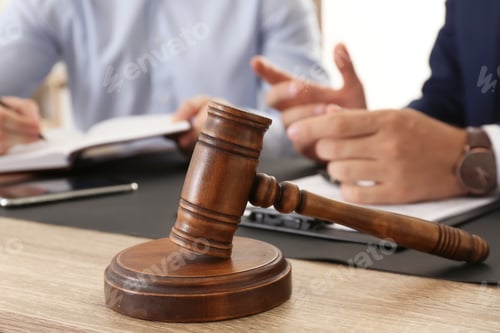 Preview: Gavel and blurred lawyer working with client on background