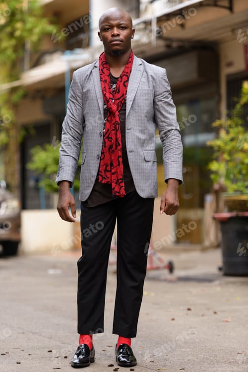Preview: Full body shot of young bald African businessman with scarf outdoors