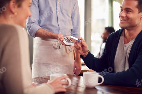 Preview: Couple In Coffee Shop Making Contactless Payment With Card For Drinks To Male Waiter
