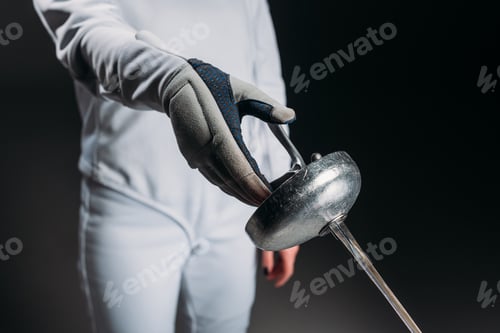 Preview: Cropped view of fencer in fencing suit and glove holding rapier isolated on black