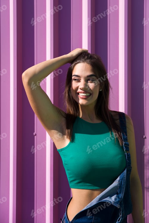 Preview: Trendy young woman standing by the pink wall