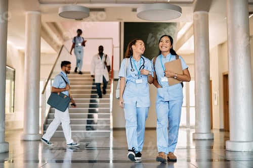 Preview: Happy female medical students walking through hallway at medical university.