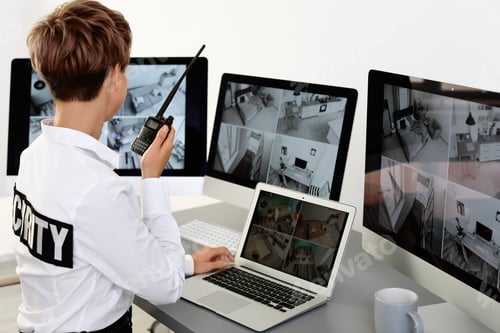 Preview: Female security guard with portable transmitter monitoring home cameras indoors