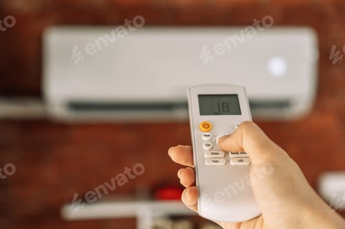 Preview: Remote control of a white air conditioner that hangs on a brick wall