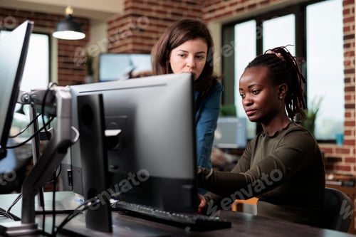 Preview: Creative company office workers sitting at desk in office workspace while discussing about graphics
